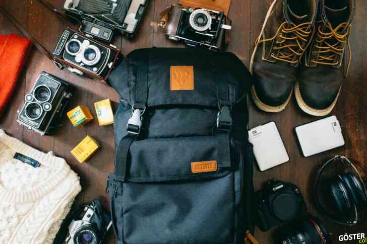 high-angle photo of black bag beside cameras, portable HDD and black leather lace-up boots