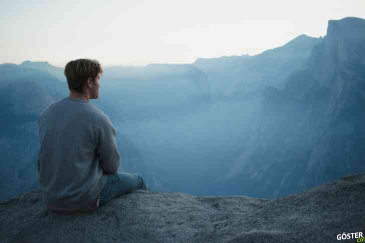 man in gray shirt sits on cliff